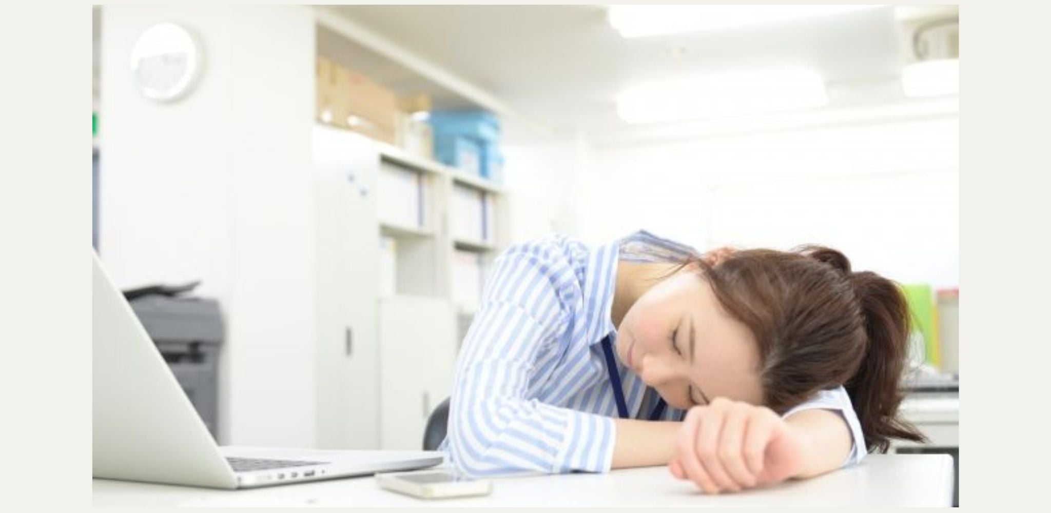 オフィスの机で居眠りする女性